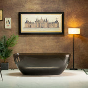 Modern black freestanding bathtub in a stylish room with a lamp and framed picture on the wall.